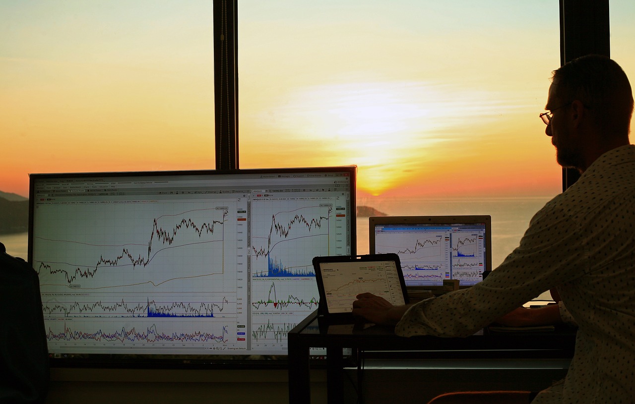Stock market computer screens against a sunset backdrop